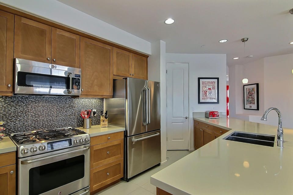 Open kitchen with 'Caesarstone' island/countertop and tile backsplash.