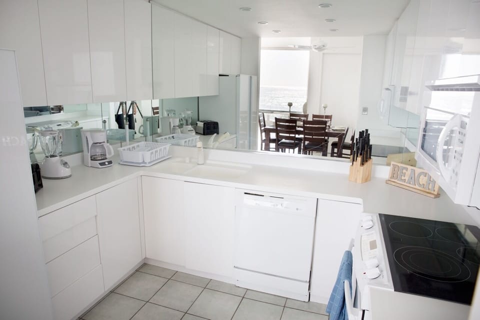 The kitchen has a dishwasher and a microwave and the mirrors bring in the view.