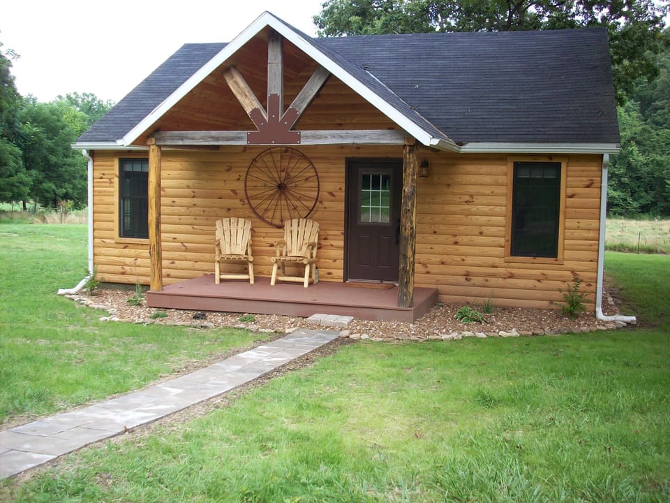 The exterior of the cabin in the summertime, with a view of the front porch.