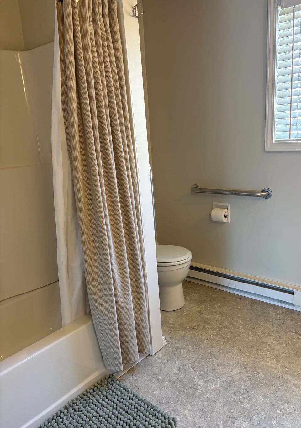 main bathroom with tub/shower and grab bars by toilet.