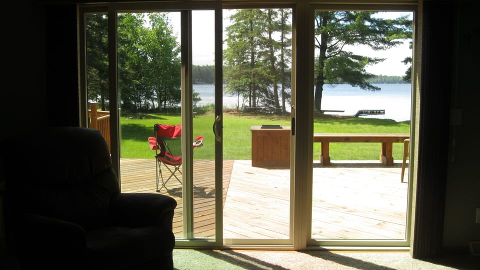 Tri panel sliding patio doors in living room walks out to deck.