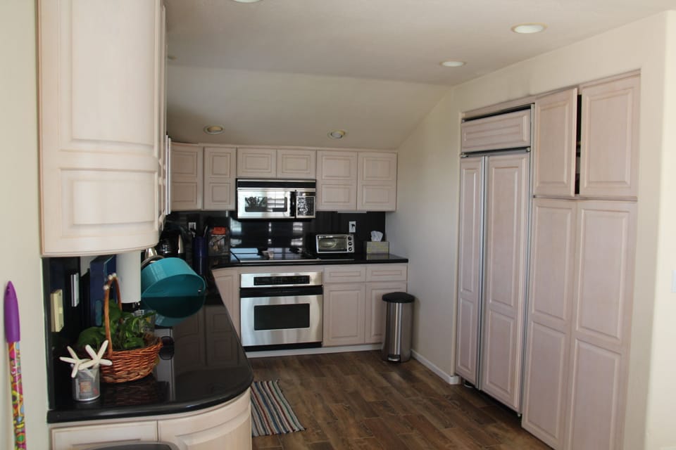 Kitchen with microwave, oven, cooktop, double door refrigerator, pantry cupboard