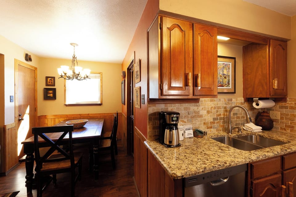 Your fully equipped kitchen with granite counters and stainless fixtures flows into a charming dining area—perfect for home-cooked meals and relaxed mornings over coffee.