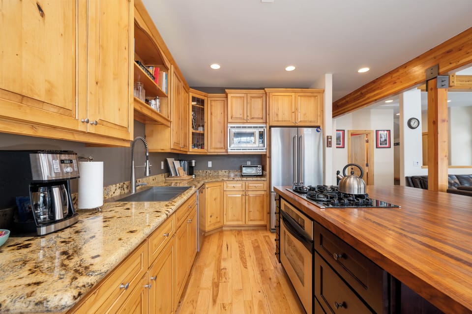 Your gourmet kitchen awaits with granite counters, stainless appliances, and warm wood finishes perfect for creating memorable meals together.