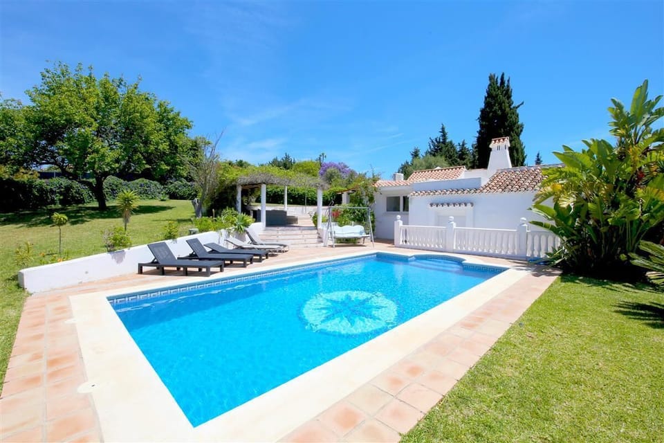 Private swimming pool with sun loungers surrounded by beautiful gardens