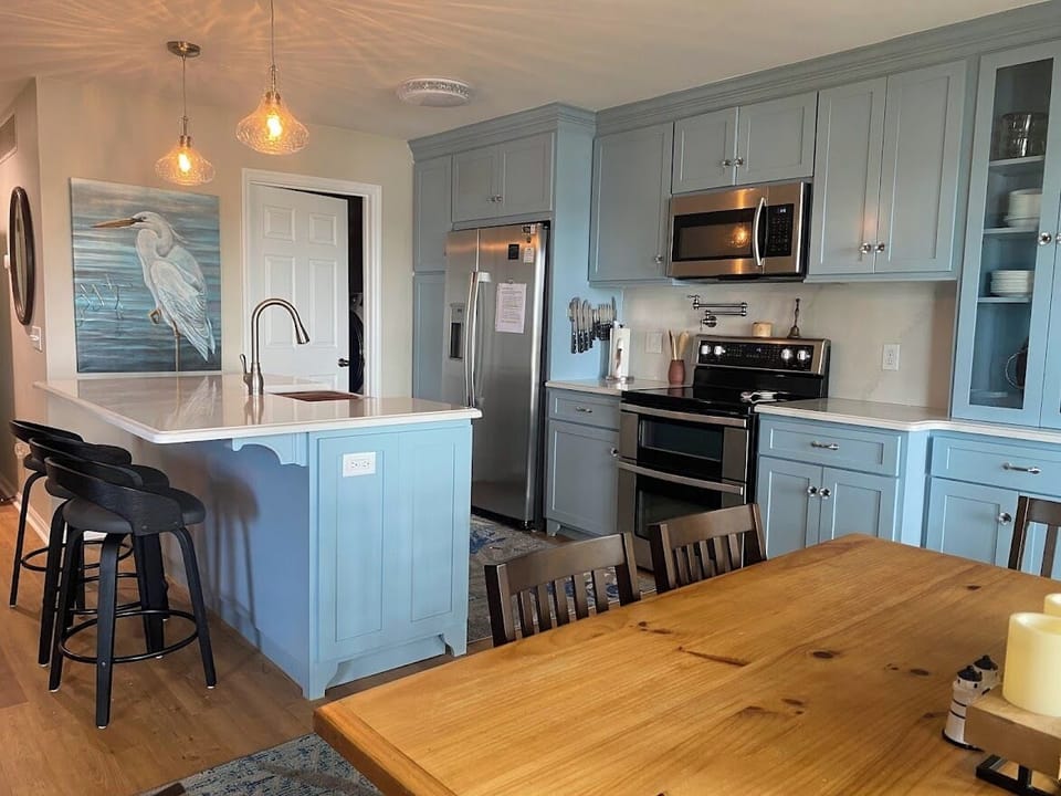 Fully stocked kitchen with a large farm sink a pot filler faucet over the stove.