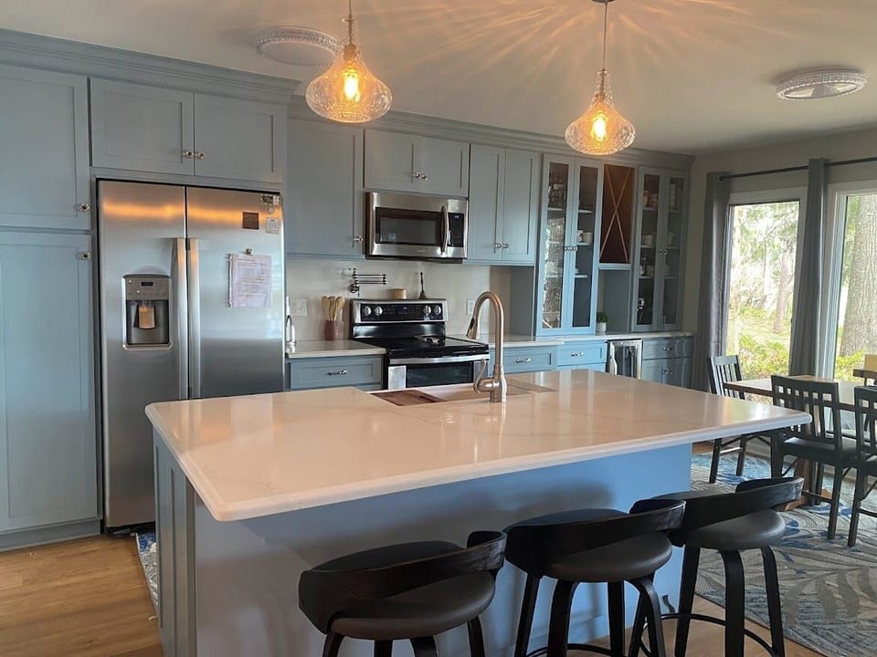 Fully stocked kitchen with a large farm sink a pot filler faucet over the stove.