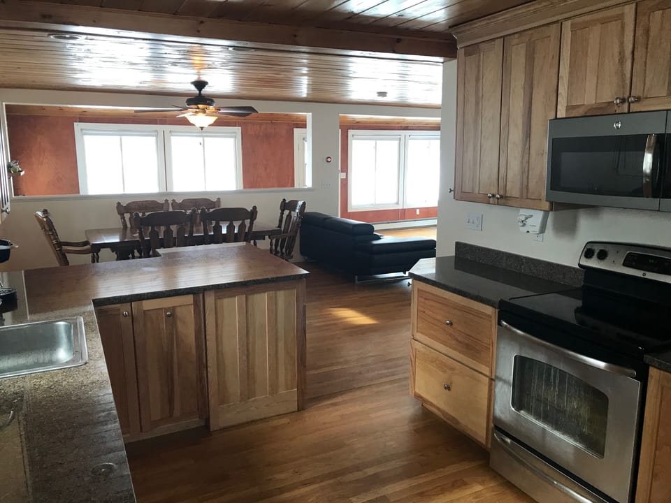 Kitchen overlooks 1st floor with open concept, SS/granite, and views of the lake