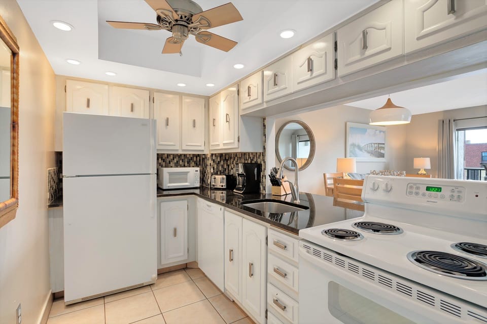 Fully equipped kitchen with charming white cabinetry and modern appliances.