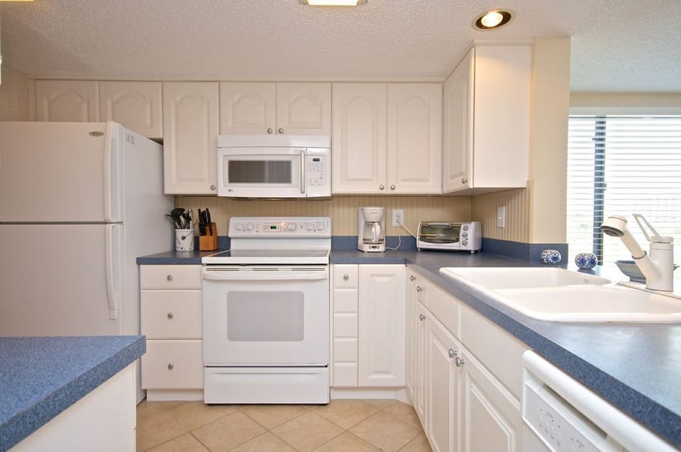 Clean kitchen that is well stocked with appliance, pots, pans and dishes.