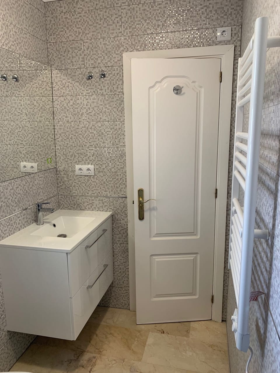 Modern en-suite bathroom with heated towel rail and extractor fan.