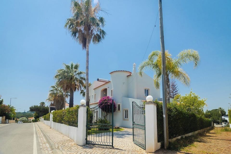 White villa entrance with palm trees and magenta bougainvillea — Villa Sara, holiday villa in Loulé
