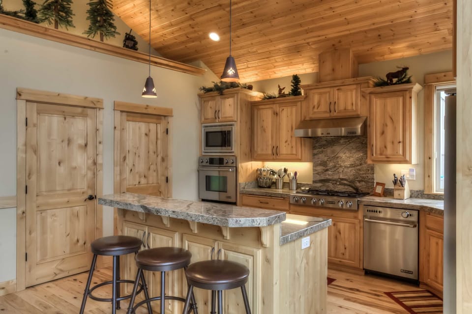 Rustic kitchen w/ wood cabinetry, stone details & bar seating