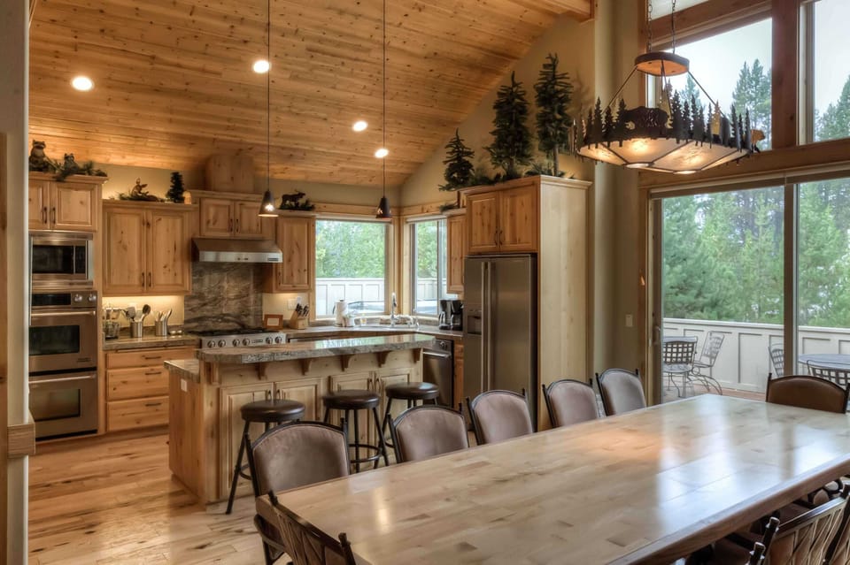 Spacious kitchen w/ island seating, wood finishes & forest views