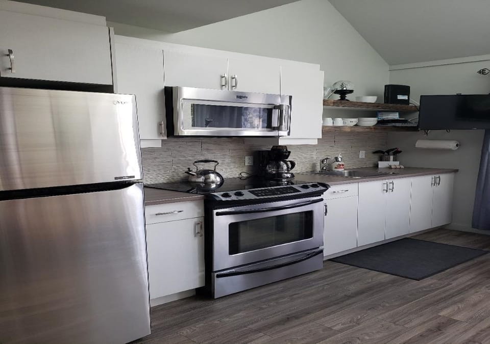 Full size kitchen stove, fridge, microwave, coffee maker, toaster, kettle.