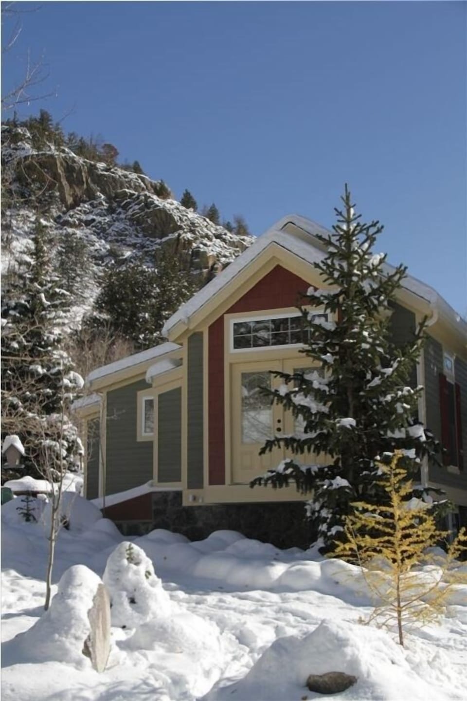 Side of cottage in winter, with mountain and hiking trails in the background.