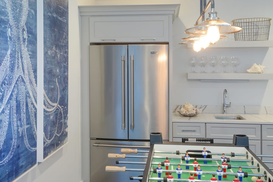 Game room with full refrigerator and freezer, sink and wine glasses