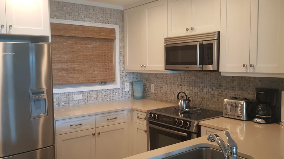 Bright kitchen with quartz countertops and all stainless appliances
