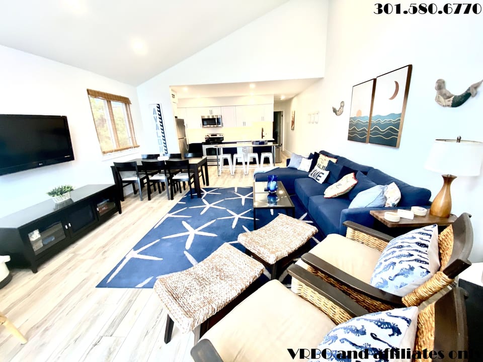 Living area with large sectional, flat panel HDTV, fireplace and 2 dining tables