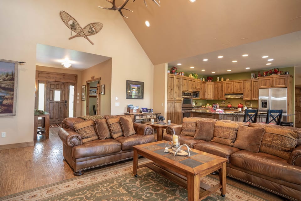 Lodge style great room with vaulted ceiling next to foyer and kitchen
