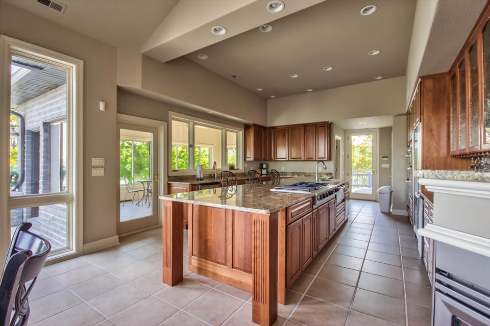 Large Kitchen with grand center island leads to pool/patio area & 3 season room