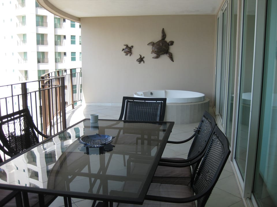 Full balcony shot: jacuzzi and table for six with ample walking room in between