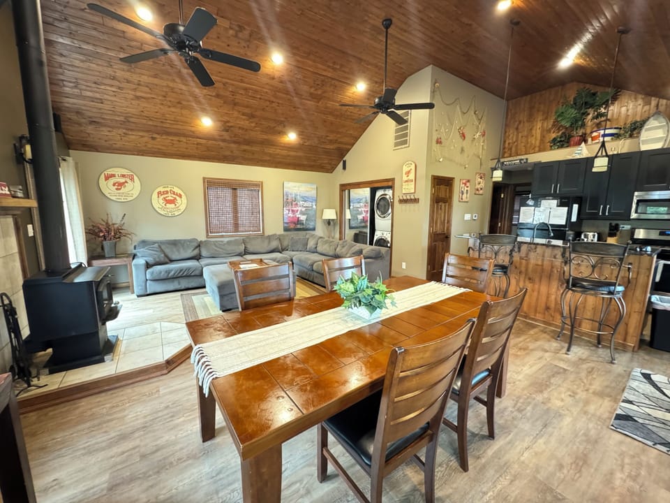 Large living room/kitchen area. Couch, Tv and wood burning fireplace.