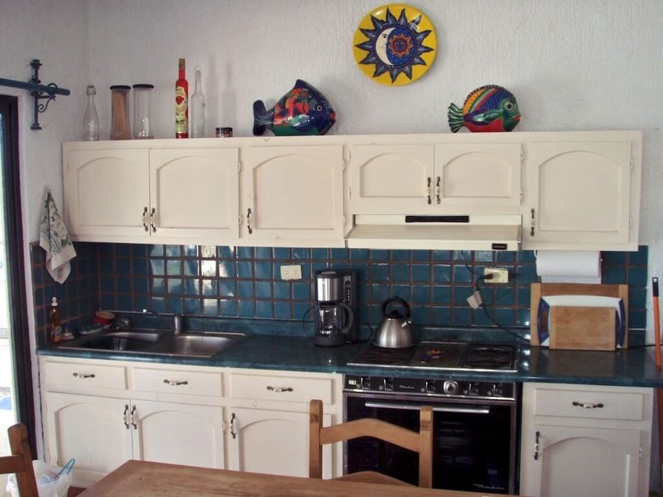 Full kitchen opens onto covered patio with dining table & chairs.