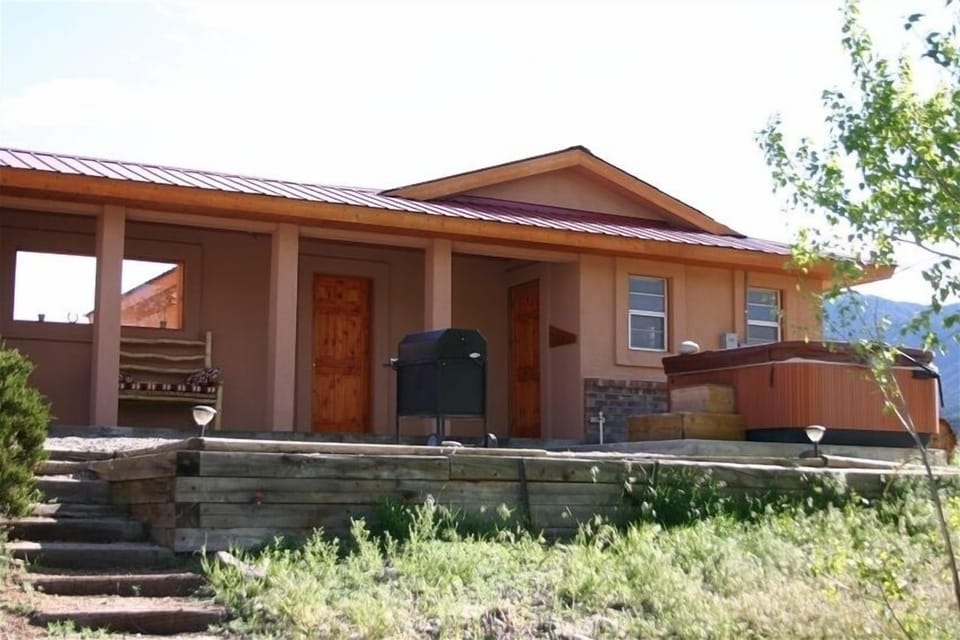 view of back of house with charcoal grill and hot tub