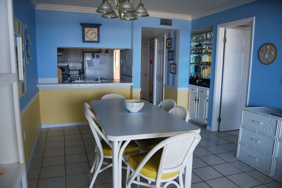 Dining table, wet bar on the right and counter window looking into into kitchen