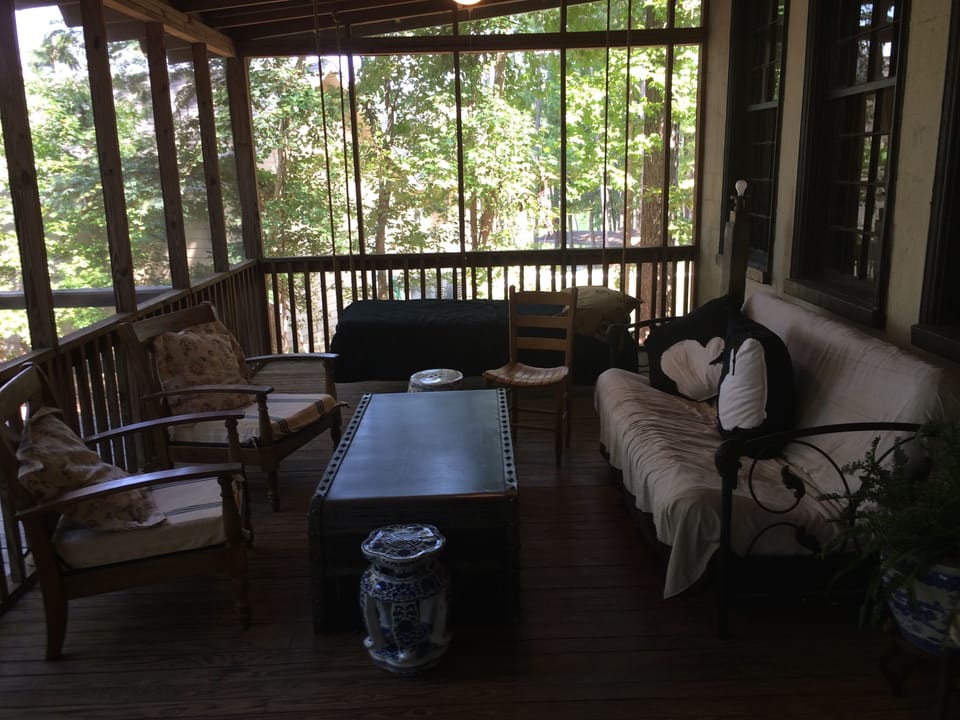 screen porch with hanging bed and futon