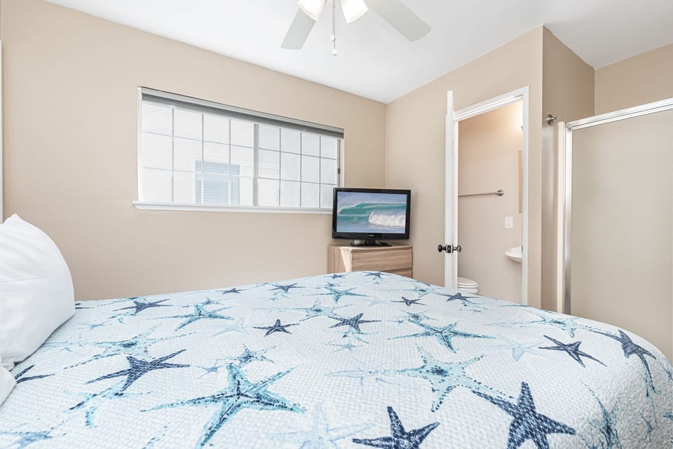 Small primary bedroom provides a Queen bed, TV, ceiling fan, and in-room bathroom and shower.
                