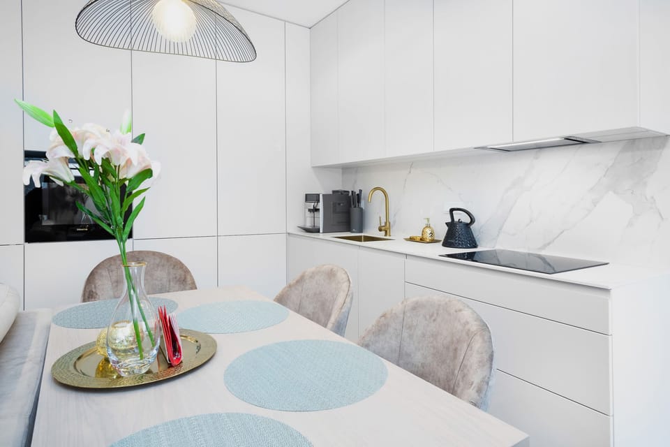 A dining area with a simple table and chairs, complemented by modern pendant lighting and a neutral color palette.