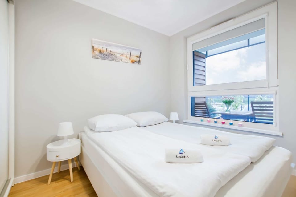 A bedroom with a neatly made bed, white bedding, and minimalist decor, creating a peaceful and relaxing ambiance.