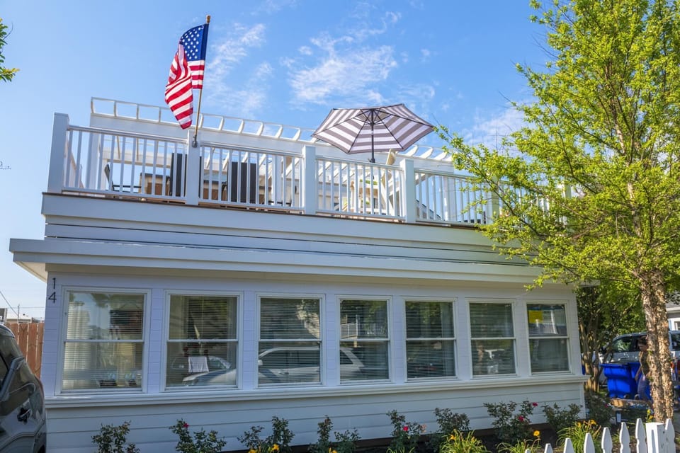 The house features a fully enclosed first-floor sunroom and a spacious second-floor rooftop deck with ocean views.