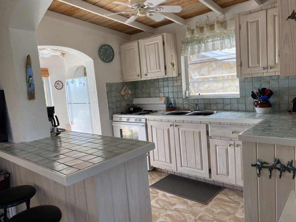 Kitchen with breakfast bar, table to the left of kitchen, utility room to right.