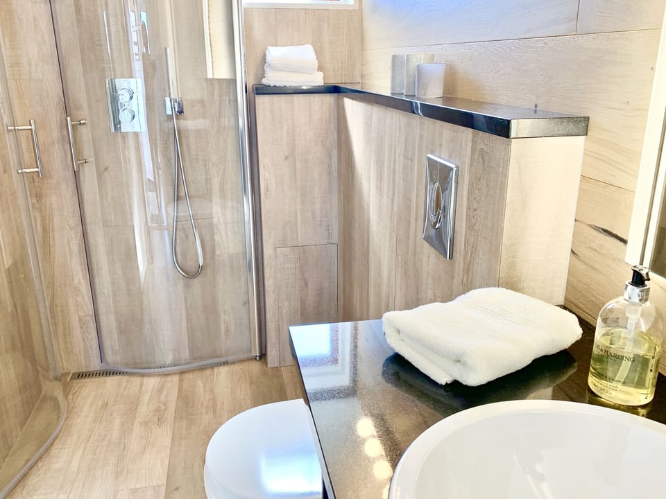 Lundur. Guest house bathroom with a shower and a warm towel rack.