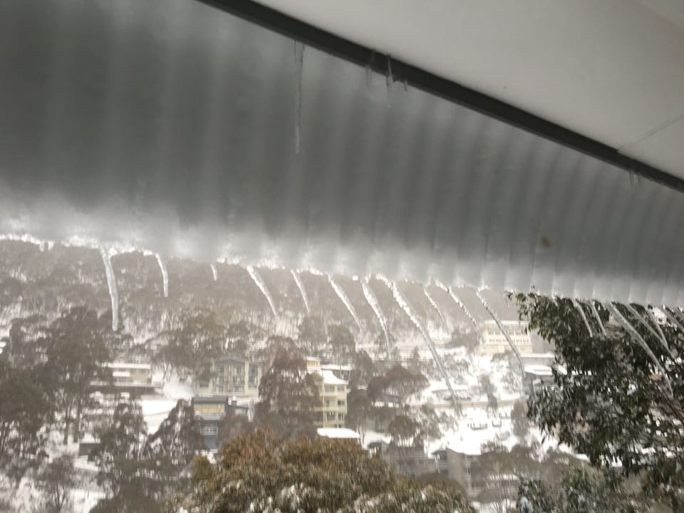 Snow forming off the roof with a view of the village from the back of the house.