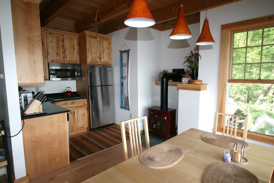 Pendant lighting over table, gas fireplace and kitchen in the background