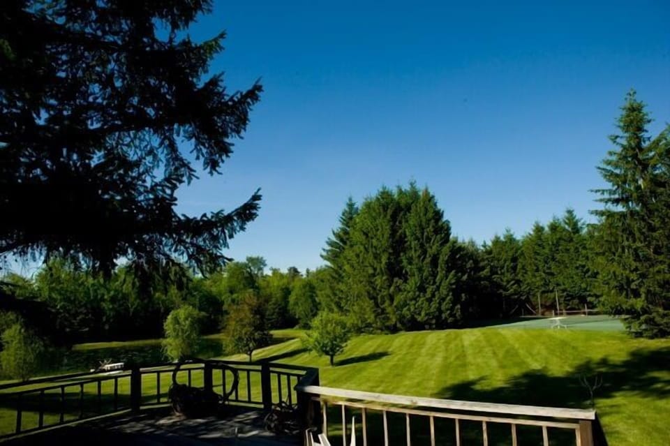 View of the lawn, pond, and tennis court from rear deck