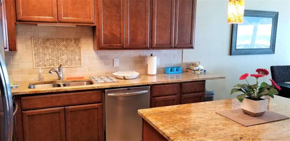 Granite countertops span the kitchen island and sink area, with cherry wood cabinets and beige tile backsplash.