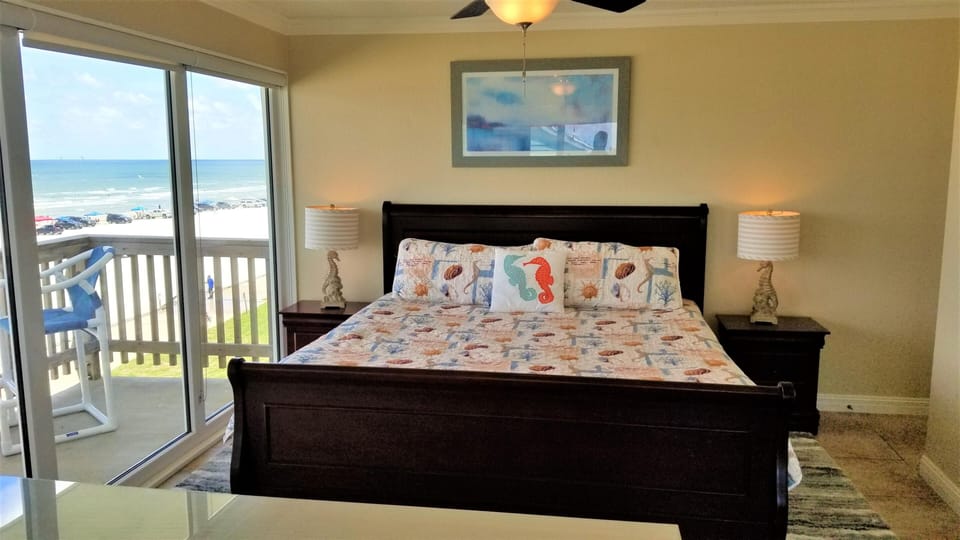 Two carved seahorse lamps with striped shades flank a dark wood bed with coastal-themed bedding.