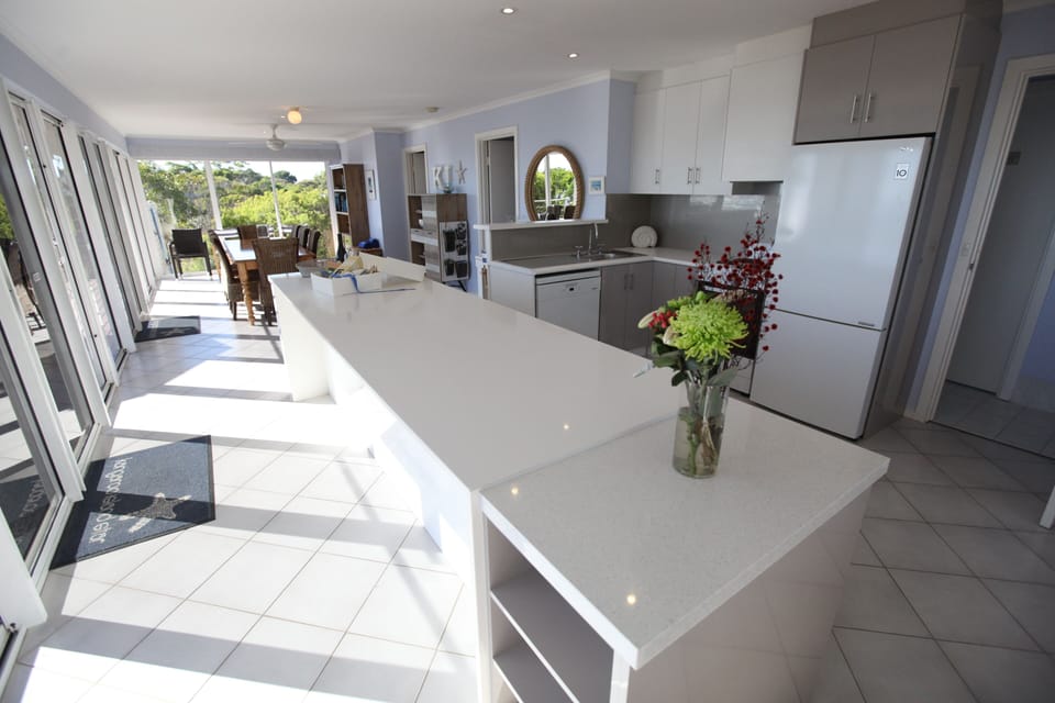 Sunfilled living room and kitchen with huge stone island bench. 