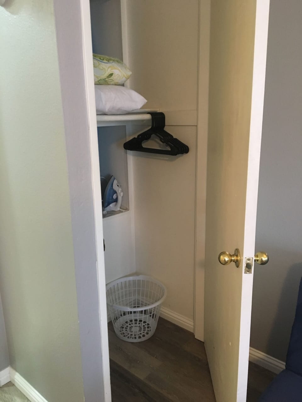 closet with hangers, iron, ironing board, and extra linens for pull-out couch