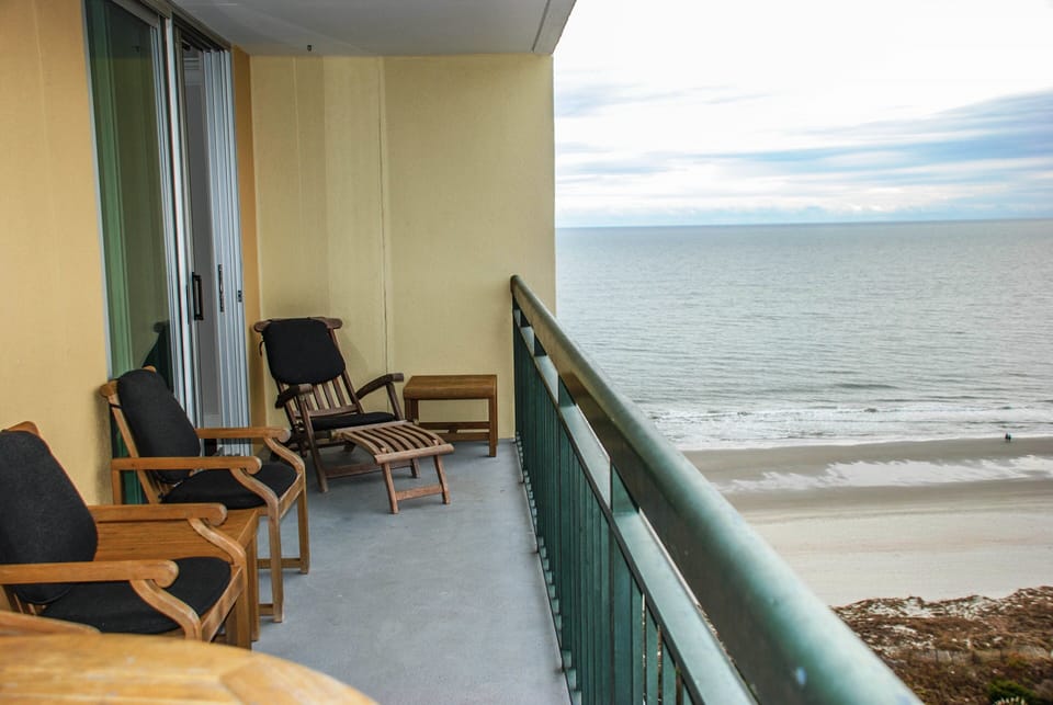 Balcony off of the living room is decked out with stylish teak furniture