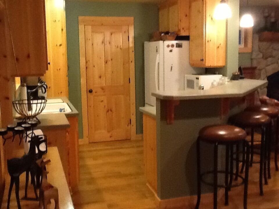 View of kitchen while standing at base of stairs. What’s behind this door?