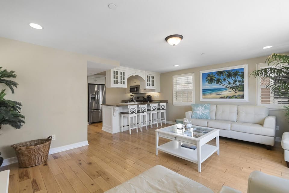 The main living area is located on the second floor and includes a leather sofa with ottoman and additional seating, cable TV, and French doors that open to a Juliet balcony with an ocean view down the street.
                