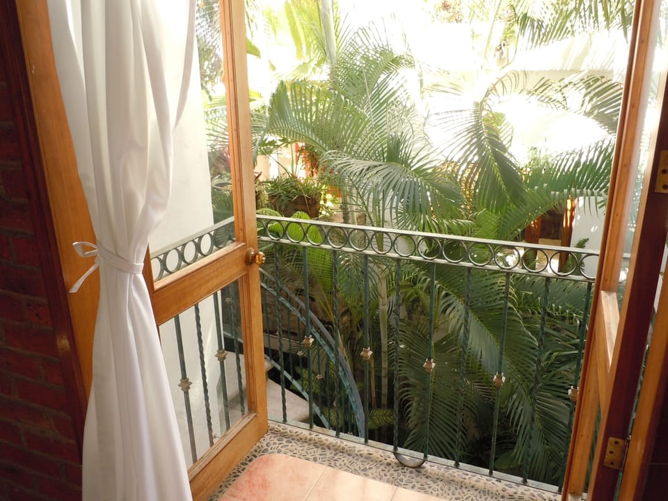 great room Juliet balcony overlooks tropical garden with a peekaboo ocean view