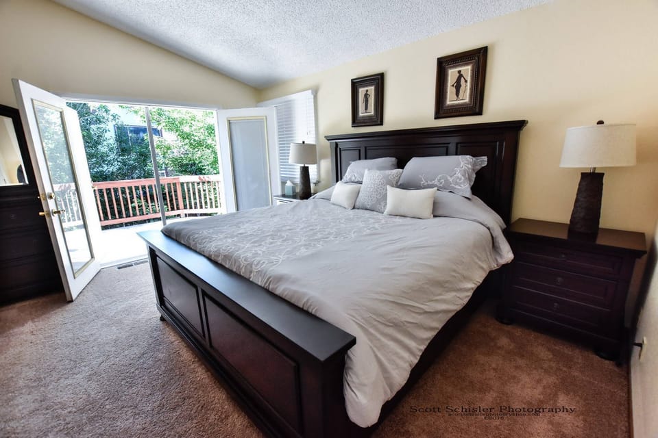 MASTER BEDROOM WITH KING BED AND BALCONY OVERLOOKING BACK YARD AND DECK