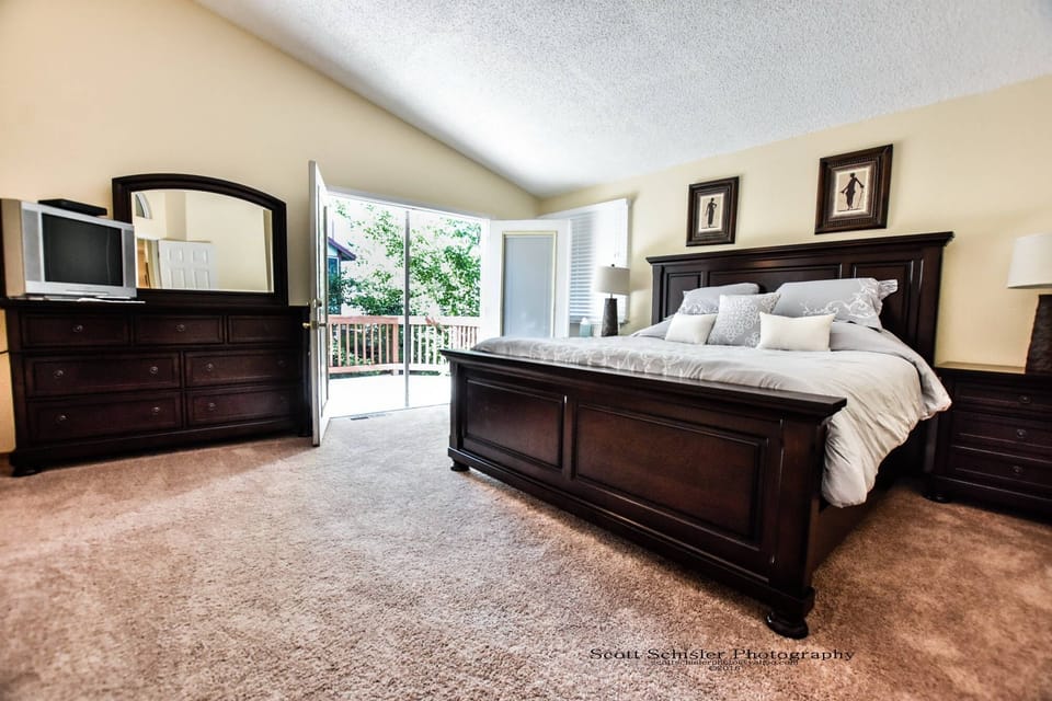 MASTER BEDROOM AND BALCONY OVERLOOKING BACK YARD AND DECK WITH ATTACHED BATH